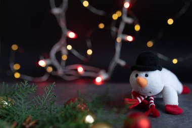 Soyut Noel ışıkları arka planında şık şapkalı ve eşarplı komik kardan adam. Tebrik kartı şablonu ve yeni yıl telif uzayı ile birlikte. Bokeh Noel ışıkları.