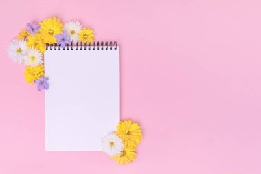 Kadınsı ofis çalışma alanı. Kopyalama alanı olan bir defter. Kopya Uzayı ile Üst Görünüm. Sosyal medya, düğün listesi konsepti. Pastel pembe arka planda güzel çiçekler.