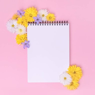 Kadınsı ofis çalışma alanı. Kopyalama alanı olan bir defter. Kopya Uzayı ile Üst Görünüm. Sosyal medya, düğün listesi konsepti. Pastel pembe arka planda güzel çiçekler.
