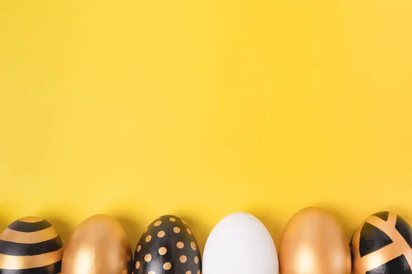 Colocación plana de huevos de Pascua dorados sobre fondo amarillo. Mínimo concepto de Pascua. Tarjeta de Pascua feliz con espacio de copia para el texto. Vista superior. Horizontal . — Foto de Stock