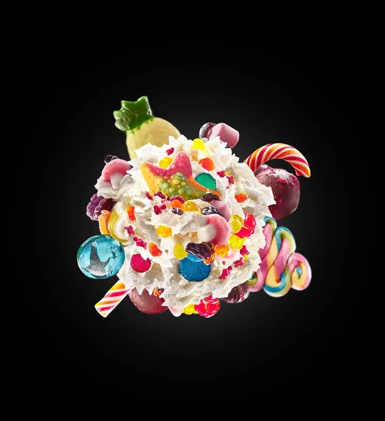 Milk shake with sweets and whipped cream, round form top view. Crazy freakshake food trend. Top view of whipped cream, full of berry and jelly sweets, chocolate candy. Colored whipped cream concept — Stock Photo, Image