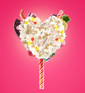 Tatlı Lolipop şeker, reçel, kalp önden görünüm ile krem şanti kalp şeklinde. Deli freakshake gıda eğilim. Çırpılmış krema lolly, berry ve jöleli şeker, çikolata tam kalbinde önden görünümü