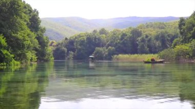 Doğal bir gölün berrak, şeffaf suları ve turistleri taşıyan küçük bir kayık..