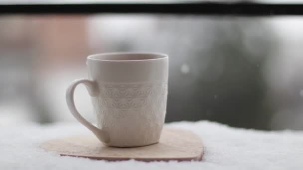 冬の雪の上の外の木製のコースターの白いカップの中のコーヒー ブラック アメリカン コーヒー おいしいコーヒー — ストック動画
