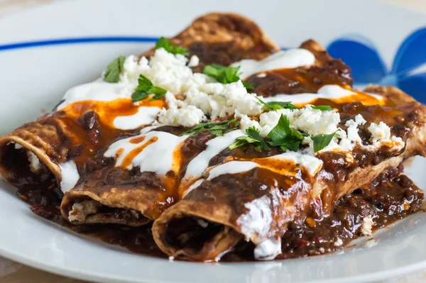 Vejetaryen Meksika yemeği, enfrijolada. Mısır tortillasına sarılı ve krema, peynir, baharatlı sos ve kişniş sosuyla kaplı baharatlı siyah fasulye sosuyla yıkanmış bir çeşit enchilada tabağı.