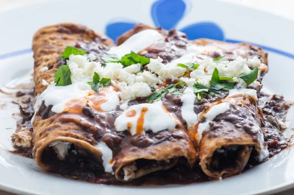 Vejetaryen Meksika yemeği, enfrijolada. Mısır tortillasına sarılı ve krema, peynir, baharatlı sos ve kişniş sosuyla kaplı baharatlı siyah fasulye sosuyla yıkanmış bir çeşit enchilada tabağı.