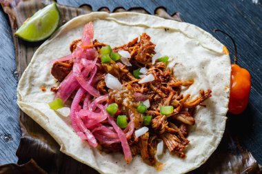 Cochinita Pibil 'in Meksika Tacoları, kızartılmış domuz eti, Yucatan usulü habanero sosu ve pembe turşulu soğan ile servis ediliyor.