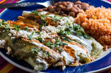 Enchiladas Verdes, ya da yeşil enchilada, tavukla doldurulmuş tortilla fasulye ve Meksika usulü pirinç ile servis edilir.