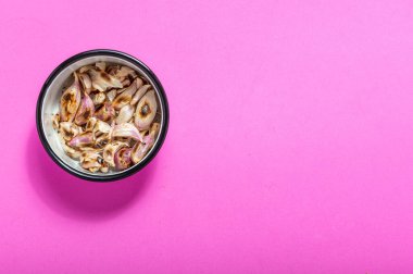Pembe arka planda diş minesi kasesinde kavrulmuş sarımsak. Pembeyle izole edilmiş. Yiyecek malzemeleri.