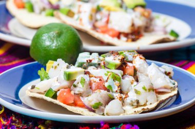 Fish ceviche, Mexican food from Peruvian origin. Raw fish marinated in lime juice with raw onion, tomato, jalapeno pepper, avocado and herbs. Served on crispy fried tortillas. clipart