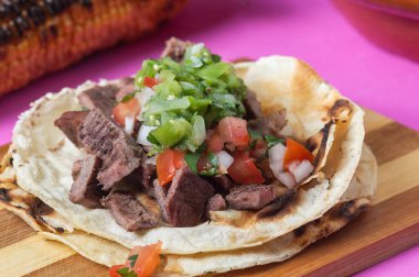 Meksika carne asada tacos, kelimenin tam anlamıyla ızgara et taco. Bunlar, salsa verde ve pico de gallo soslu yumuşak mısır totillalarında servis edilen ızgara sığır eti.