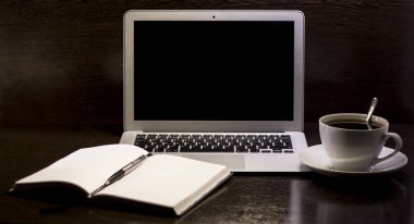Notebook on the table. Near the laptop. Cup of coffee.
