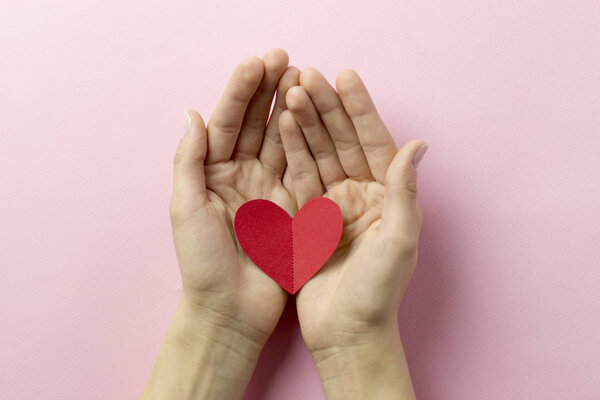 Красное свинцовое сердце в женских заботливых руках
