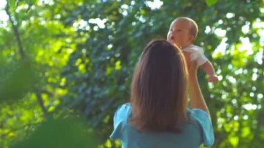 Mutlu anne bebeği kollarında tutuyor ve onunla dönüyor.