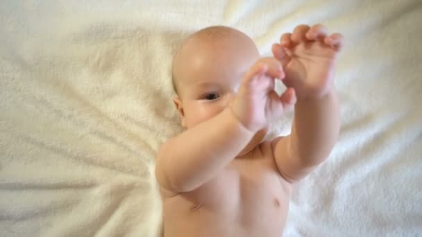 赤ん坊のクローズアップ 子供は嘘をつき手を振ってカメラを見る — ストック動画