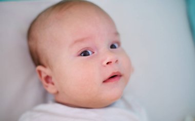  Yatakta bir bebeğin portresi, kameraya bakan bir çocuk.                              