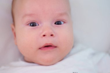   Yatakta bir bebeğin portresi, kameraya bakan bir çocuk.                      