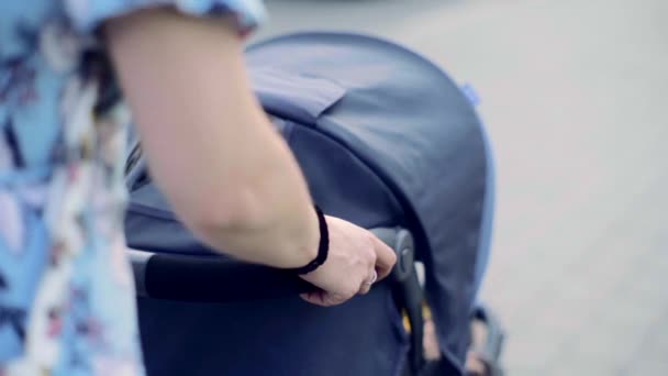 若いブルネットの女性は通りの下の赤ん坊の馬車と歩いていると周りを見ている スローモーション — ストック動画