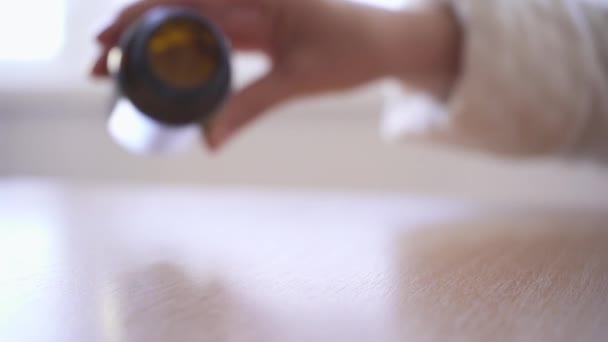 Gros plan d'une main de femme versant des pilules blanches d'une bouteille sur une table. Pilules abandonner au ralenti .