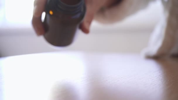 Gros plan d'une main de femme versant des pilules blanches d'une bouteille sur une table. Pilules abandonner au ralenti .
