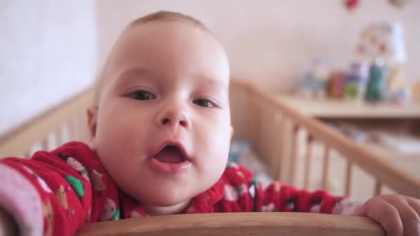 Bebé Gracioso Para Cama Mira Cámara Niño Estira Las Manos — Vídeo de stock