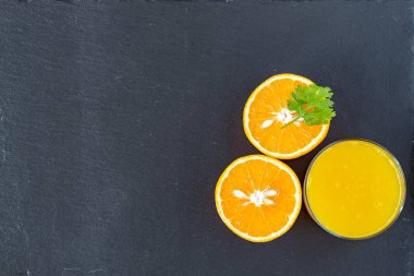 Bir bardak portakal suyu ve portakal suyu ikiye bölünmüş.