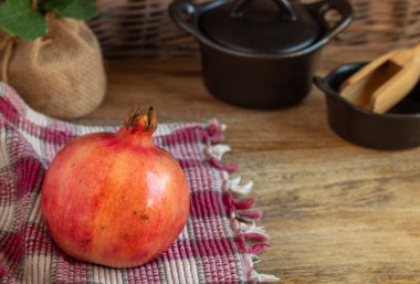 Nar, kesme tahtasında kırmızı meyve, kil kaplar ve bez parçaları.