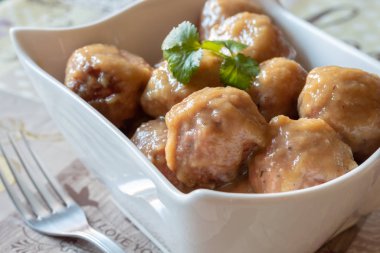 Beyaz kasenin üzerinde soğan soslu ev yapımı domuz eti köftesi.