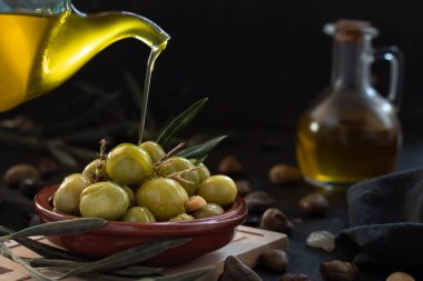 Masa zeytinlerinin üzerine dökülen yağları siyah bir kaseye döküyorlar.