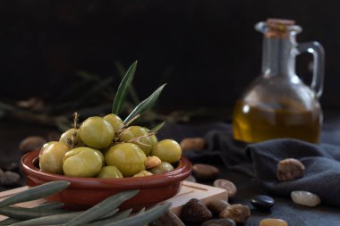 Yağlı ve siyah arkaplanlı kil kasede masa zeytinleri