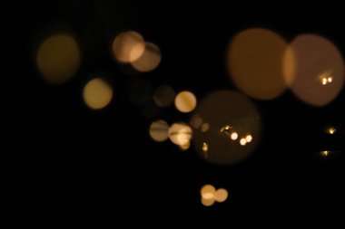 Parlak odağını kaybetmiş, siyah arkaplanda altın ve sarı ışıklar