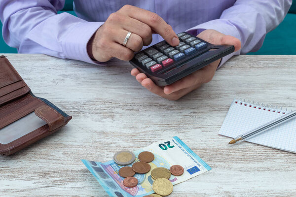 Young man calculates family accounts with the calculator during the crisis following the covid-19 pandemic