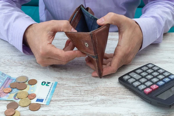 Young man searches his wallet for money during the economic crisis following the covid-19 pandemic