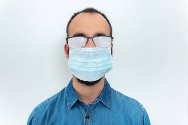 Kot gömlekli, maskeli ve beyaz arka planda sisli gözlüklü adam.