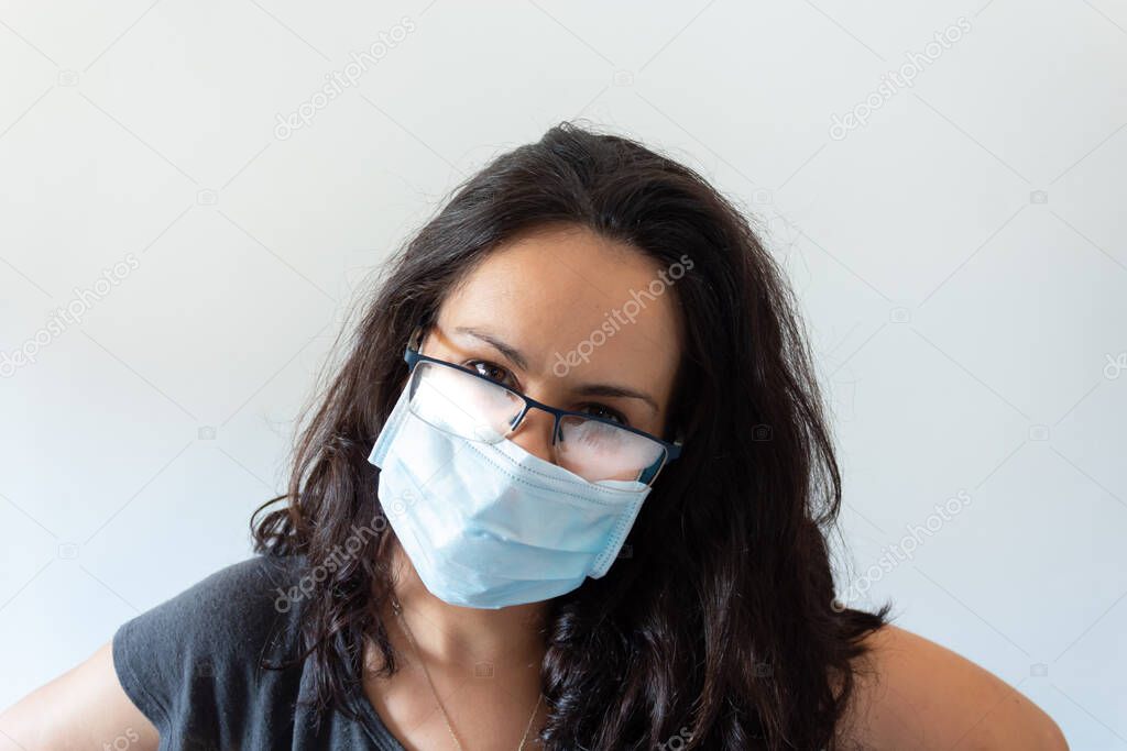 Tired woman wearing black t-shirt, face mask and misted glasses on white background