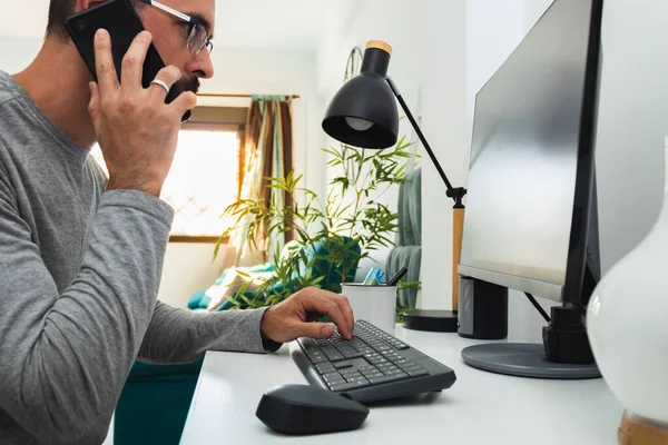 Man working from home with computer and mobile phone