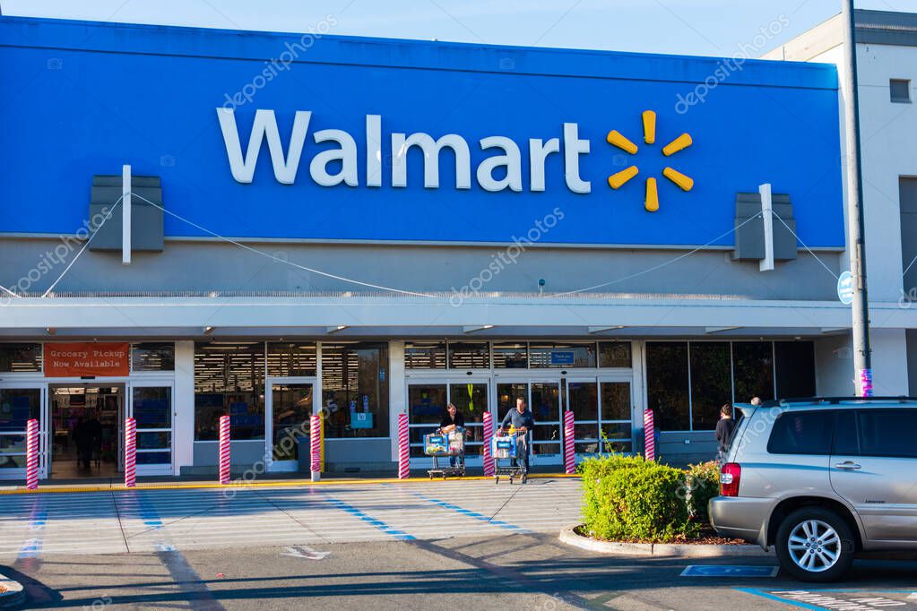 Happy customers leaving Walmart store with full shopping carts. Anti ram raiding bollards secure Wal-mart entrance from accident or theft - Mountain View, California, USA - November, 2019
