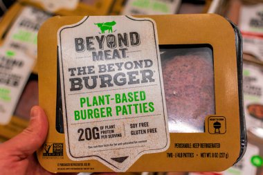A vegetarian shopper holds a package of Beyond Meat Burger packag clipart