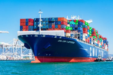 Römorkör, konteyner gemisi Cma Cgm 'e Oakland Limanı' ndan mavi gökyüzünün altında yardım ediyor.