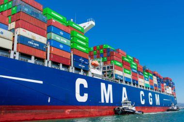 Römorkör, konteyner gemisi Cma Cgm 'e Oakland Limanı' ndan mavi gökyüzünün altında yardım ediyor.