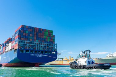 Römorkör, konteyner gemisi Cma Cgm 'e Oakland Limanı' ndan mavi gökyüzünün altında yardım ediyor.