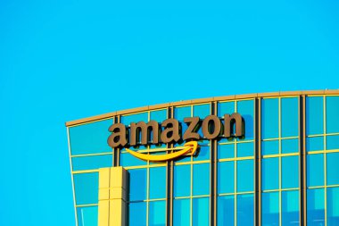 Amazon logosu modern şirket kampüsünün cam cephesinde kendine özgü turuncu gülüşüyle.
