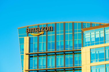 Amazon logosu modern şirket kampüsünün cam cephesinde kendine özgü turuncu gülüşüyle.