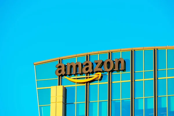 Logotipo de Amazon con su característica sonrisa naranja en la fachada de vidrio del campus de la empresa moderna —  Fotos de Stock