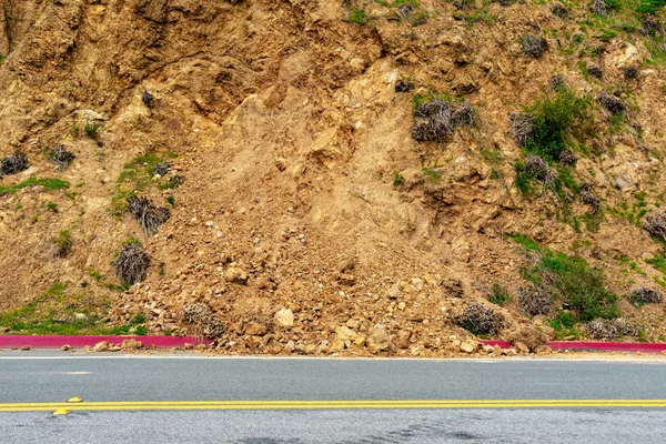 Landslide debris on rural road from steep slope after winter rain storm.