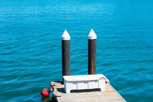 Kleiner Bootsanleger mit zwei Holzpfählen. Aufbewahrungsbox. runde rote Boje. ruhige Wasseroberfläche — Stockfoto