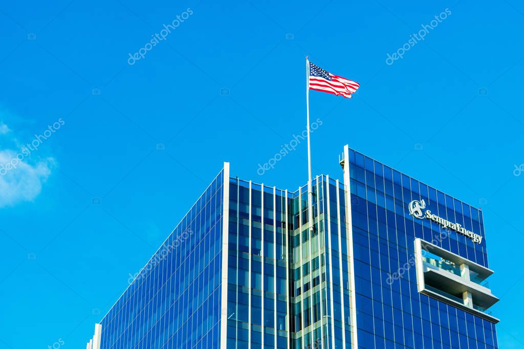 Sempra Energy corporate headquarters building facade. U.S. Flag proudly waving atop energy infrastructure company office under blue sky - San Diego, California, USA - Circa, 2018