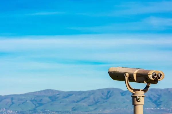 Telescopio binocular operado por monedas para visión a distancia. Borrosa gama de verdes colinas, montañas en la distancia bajo el cielo nublado — Foto de Stock