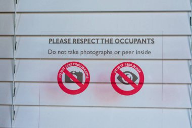 Sign prohibiting taking pictures and peering inside of the window with closed shutters notifies visitors and tourists that photography is not allowed
