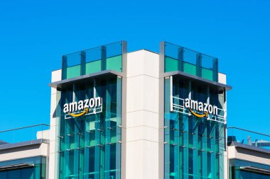 Amazon logosu, Silikon Vadisi 'ndeki şirket kampüsünün cam cephesinde imzalı turuncu gülüşüyle.